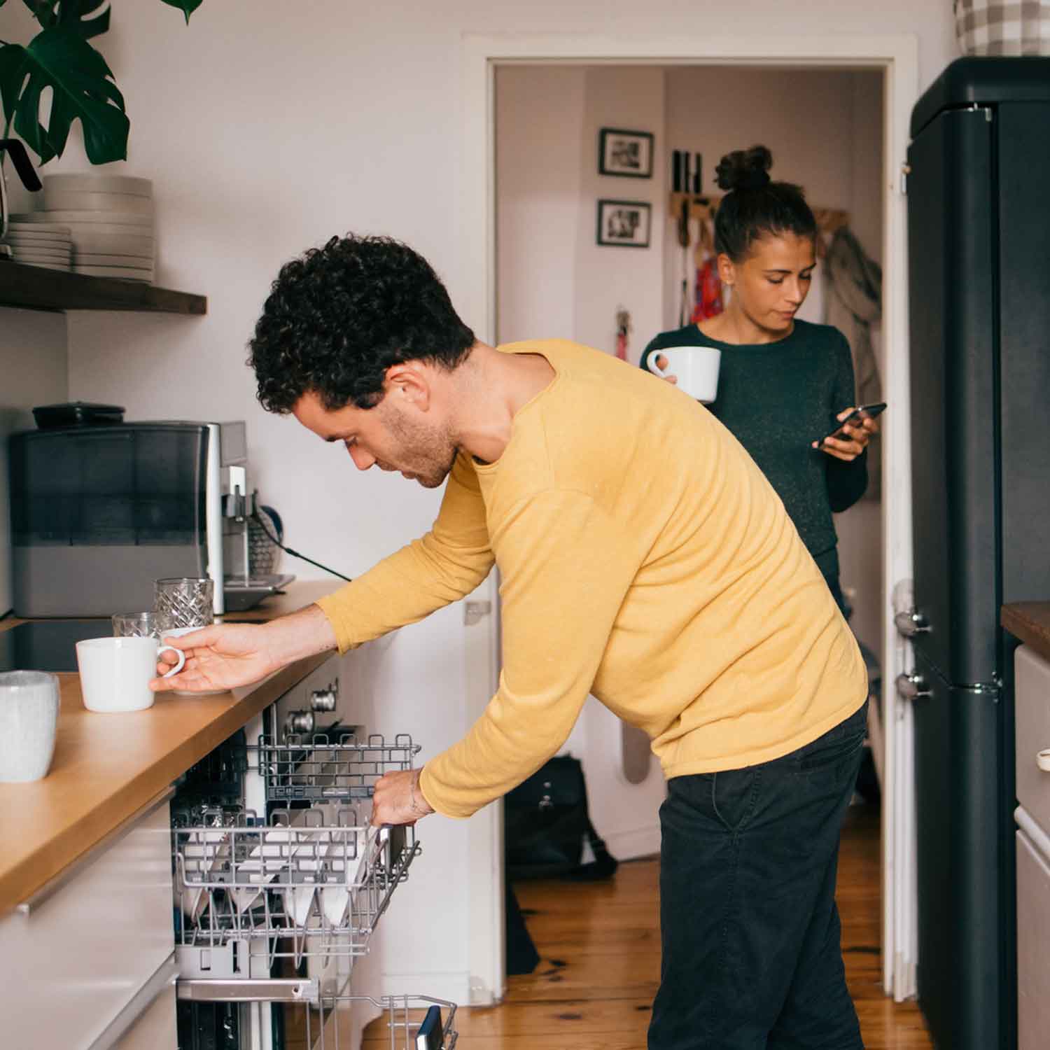 Ett frilansande par där den ena arbetar från hemmet medan den andra städar köket