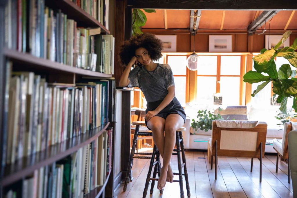 A freelancer sitting on a stool in her home office library