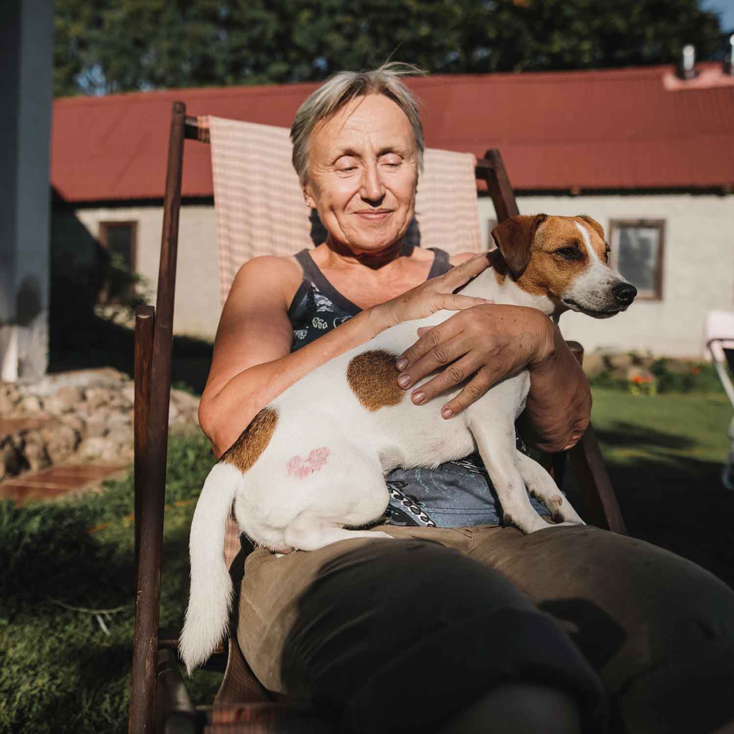 A sole trader sitting outside in the sun with her dog